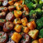 Honey garlic sheet pan sausage with roasted bell peppers, red onion, and zucchini on a parchment-lined baking sheet