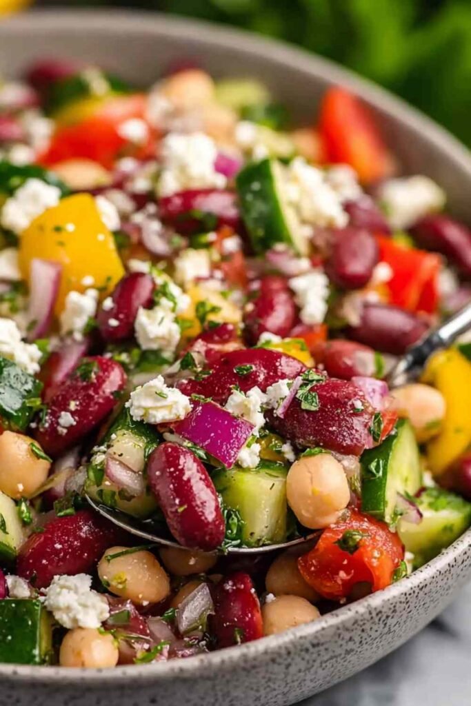 Zesty Mediterranean Bean Salad with Feta 5 A large white bowl of Mediterranean Bean Salad with Feta, chickpeas, cherry tomatoes, cucumbers, Kalamata olives, and fresh parsley