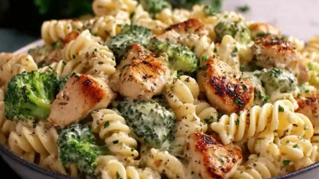 Creamy chicken broccoli pasta in a large skillet topped with grated Parmesan cheese