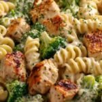 Creamy chicken broccoli pasta in a large skillet topped with grated Parmesan cheese
