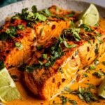 Creamy harissa salmon fillets simmering in coconut harissa sauce in a skillet