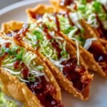 Crispy chicken wonton tacos with teriyaki glaze topped with shredded cabbage, green onions, and sesame seeds on a wooden serving board