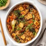 Dump and bake teriyaki tofu rice casserole in a 9x13 baking dish topped with toasted sesame seeds and sliced green onions