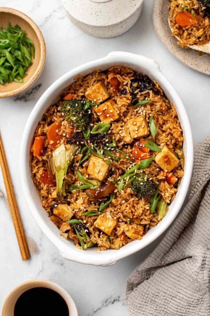 Dump and bake teriyaki tofu rice casserole in a 9x13 baking dish topped with toasted sesame seeds and sliced green onions