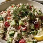 Overhead view of Greek Tzatziki Chicken Salad with shredded chicken, fresh cucumber, cherry tomatoes, red onion, and chopped almonds in a white bowl