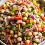 Grinder Dense Bean Salad with garbanzo beans, salami, pepperoncini, and bell peppers tossed in red wine vinaigrette in a large white bowl