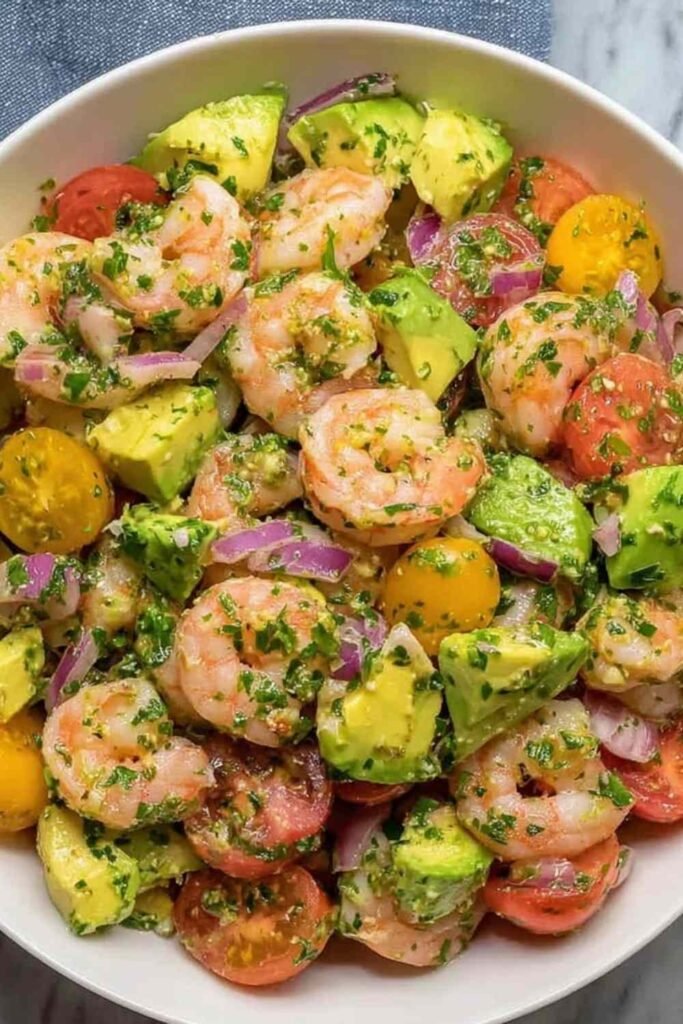 Healthy shrimp avocado salad with lime dressing served in a white bowl, overhead view
