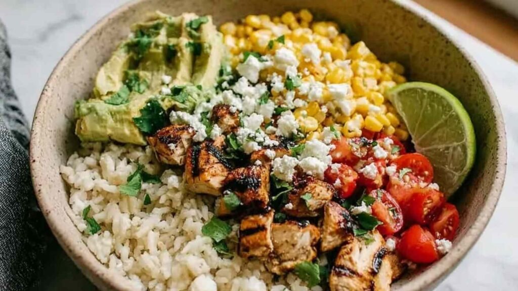 Healthy Street Corn Chicken Rice Bowl 7 Healthy street corn chicken rice bowl with sliced grilled chicken, creamy elote corn topping, avocado, and cotija cheese served over fluffy white rice
