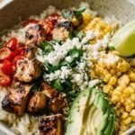Healthy Street Corn Chicken Rice Bowl 9 Healthy street corn chicken rice bowl with sliced grilled chicken, creamy elote corn topping, avocado, and cotija cheese served over fluffy white rice