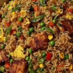 High protein crispy garlic chicken fried rice in a skillet with golden crispy rice, seared chicken, scrambled eggs, and green onions