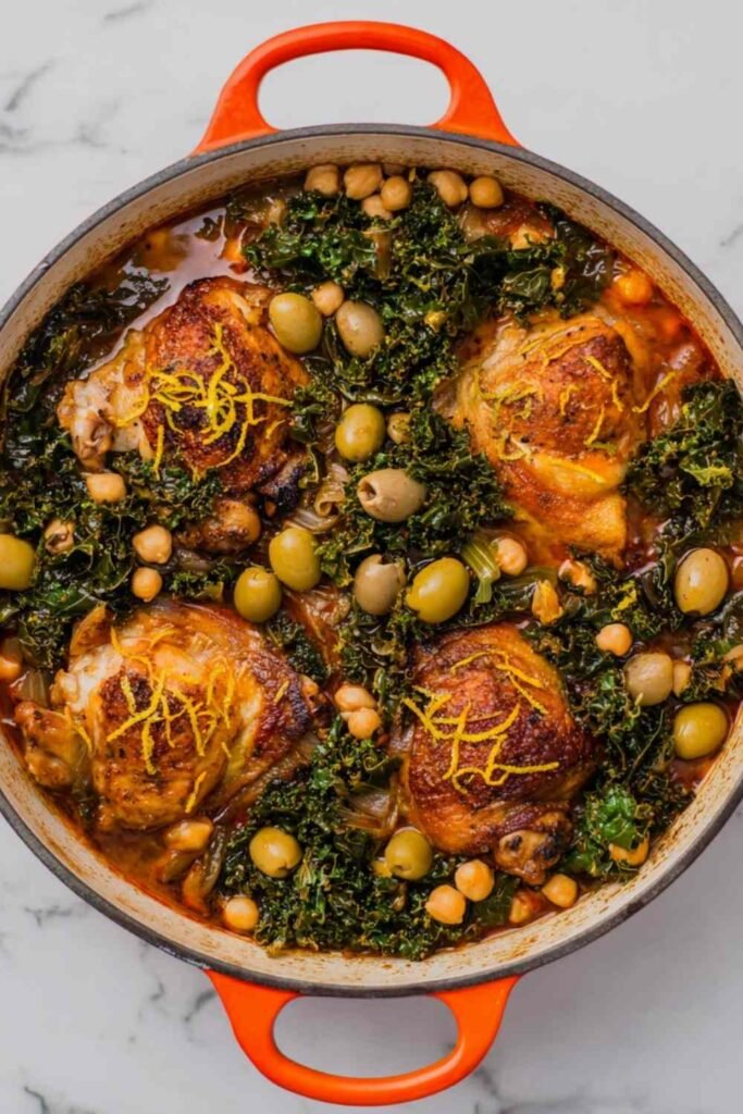 High Protein Moroccan Braised Chicken with Olives served on a white platter garnished with fresh cilantro and lemon rounds