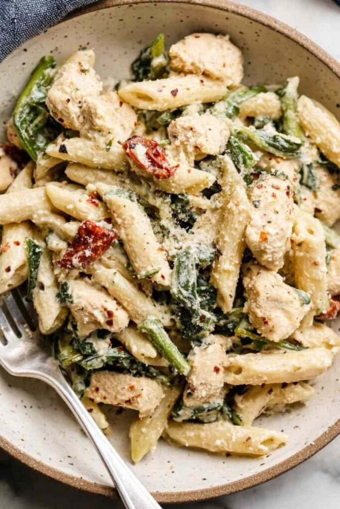 High Protein Pasta 29 Creamy high protein pasta with Cajun chicken, sun-dried tomatoes, and spinach in a white bowl