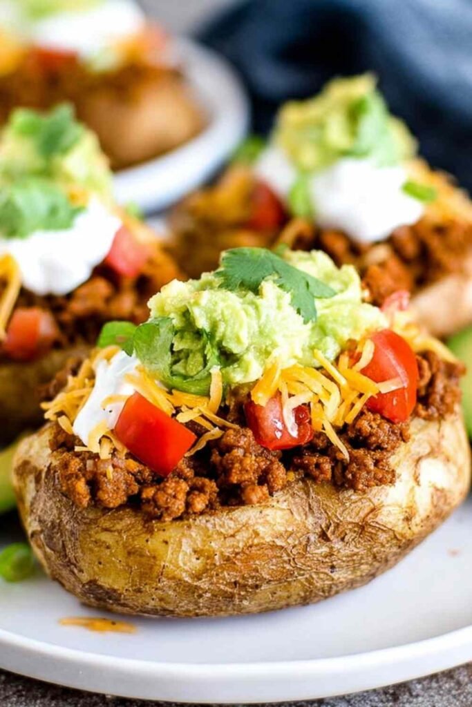 Taco Potatoes 29 Loaded taco potatoes topped with seasoned ground beef, shredded cheddar, sour cream, and fresh vegetables on a rustic plate