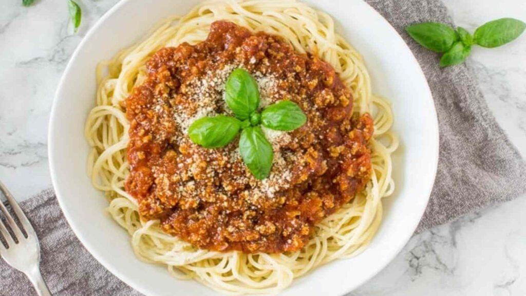 High Protein Tempeh Bolognese 16 Bowl of high protein tempeh bolognese over chickpea pasta topped with fresh basil and cashew parmesan