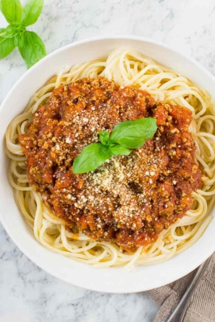 High Protein Tempeh Bolognese 17 Bowl of high protein tempeh bolognese over chickpea pasta topped with fresh basil and cashew parmesan