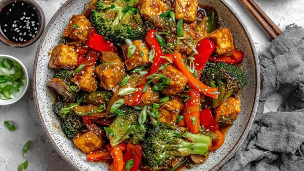 High Protein Tempeh Stir-Fry 1 High protein tempeh stir-fry with edamame and broccoli in a wok, garnished with sesame seeds and green onions