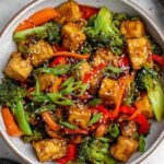 High Protein Tempeh Stir-Fry 3 High protein tempeh stir-fry with edamame and broccoli in a wok, garnished with sesame seeds and green onions