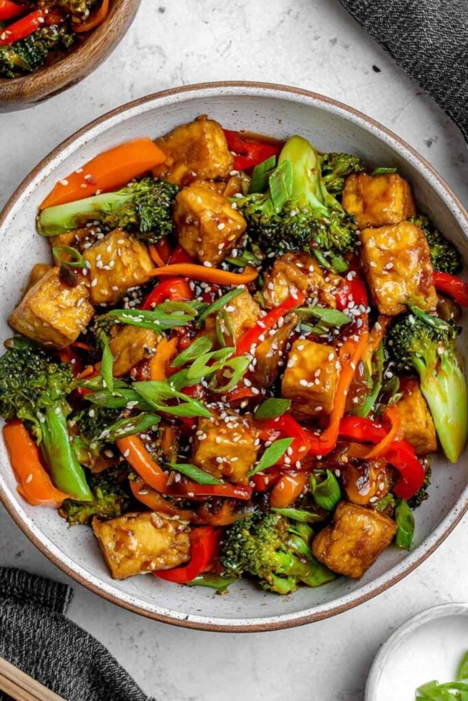 High Protein Tempeh Stir-Fry 2 High protein tempeh stir-fry with edamame and broccoli in a wok, garnished with sesame seeds and green onions