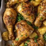 Golden sticky honey and mustard chicken drumsticks with roasted Yukon Gold potatoes on a parchment-lined baking tray garnished with fresh parsley