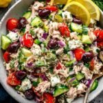 Mediterranean tuna salad with cherry tomatoes, cucumber, olives, and fresh parsley in a white bowl