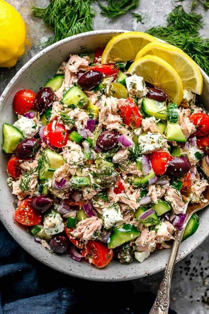 Mediterranean tuna salad with cherry tomatoes, cucumber, olives, and fresh parsley in a white bowl
