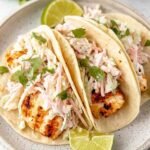 Quick Grilled Fish Tacos with Cabbage Slaw 30 Assembled quick grilled fish tacos with cabbage slaw on corn tortillas, topped with fresh cilantro and lime wedges