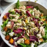 Roasted Veggie and Chicken Glow Bowl with arugula, beets, feta, and golden roasted vegetables on a white plate