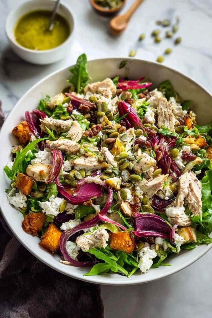Roasted Veggie and Chicken Glow Bowl with arugula, beets, feta, and golden roasted vegetables on a white plate