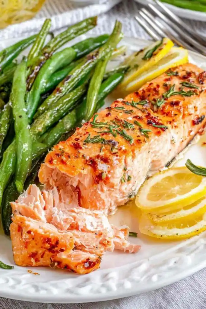 Salmon and Green Beans Sheet Pan Dinner 17 Overhead view of salmon and green beans sheet pan dinner with four seasoned fillets and roasted green beans on a parchment-lined baking sheet