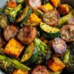 Sausage veggie skillet bowl with browned Italian sausage, zucchini, and bell peppers in a cast iron skillet garnished with fresh basil