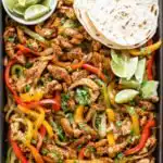 Sheet Pan Chicken Fajitas 3 Sheet pan chicken fajitas with seasoned chicken strips, roasted red yellow and green bell peppers, and fresh cilantro on a large baking sheet