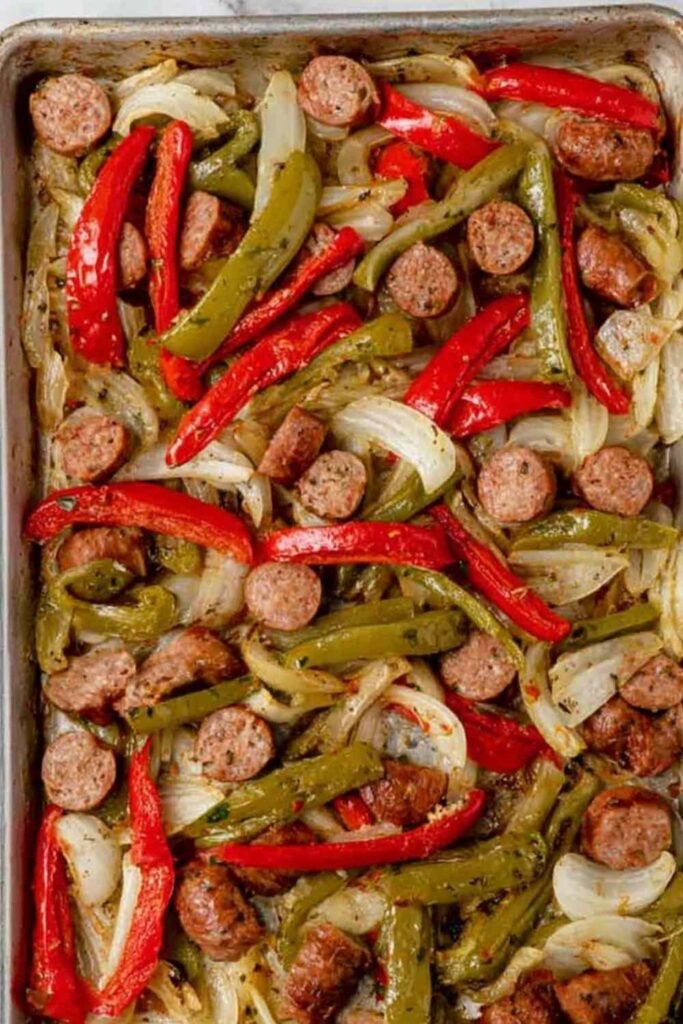 Sheet pan sausage and peppers with colorful roasted Italian sausage, red and yellow bell peppers, and red onion on a parchment-lined baking sheet