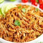 Shredded Mexican Chicken (Instant Pot and Slow Cooker) 15 Bowl of shredded Mexican chicken coated in smoky chipotle tomato sauce garnished with fresh cilantro and lime wedges