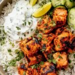 Tandoori Salmon Rice Bowls 21 Tandoori salmon rice bowl with fluffy basmati rice, sauteed vegetables, fresh cilantro, and lime wedges in a white bowl