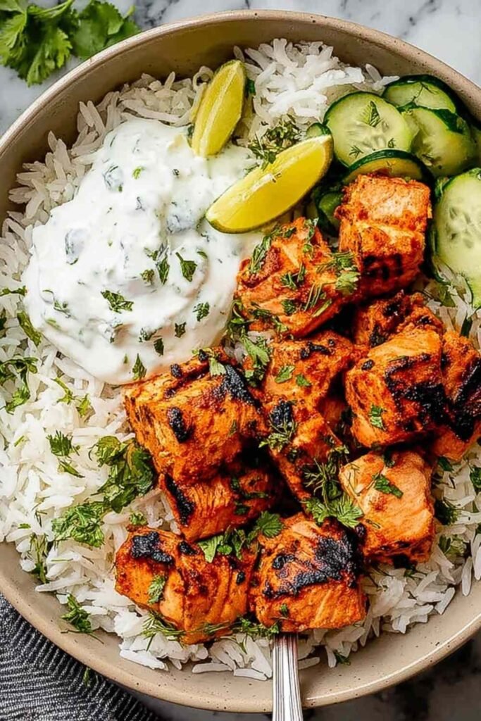 Tandoori Salmon Rice Bowls 20 Tandoori salmon rice bowl with fluffy basmati rice, sauteed vegetables, fresh cilantro, and lime wedges in a white bowl