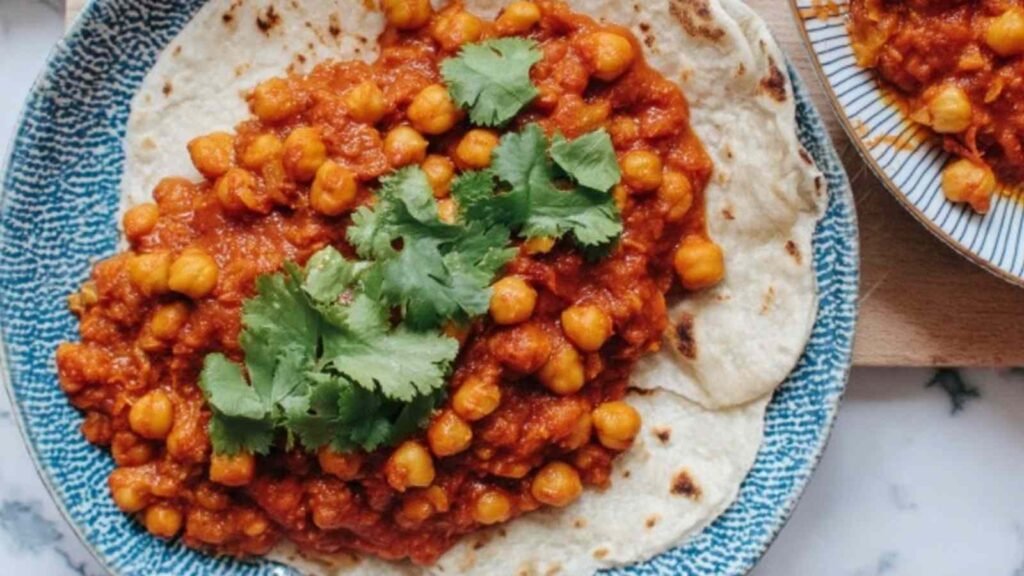 Bowl of tea infused vegan chana masala with chickpeas in a thick spiced tomato sauce garnished with fresh parsley