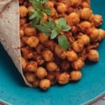Bowl of tea infused vegan chana masala with chickpeas in a thick spiced tomato sauce garnished with fresh parsley