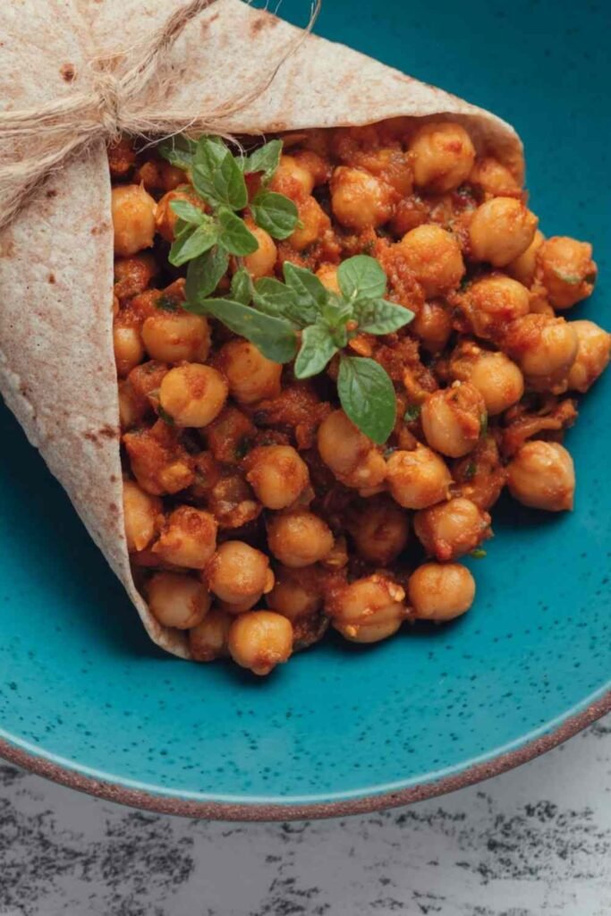 Bowl of tea infused vegan chana masala with chickpeas in a thick spiced tomato sauce garnished with fresh parsley
