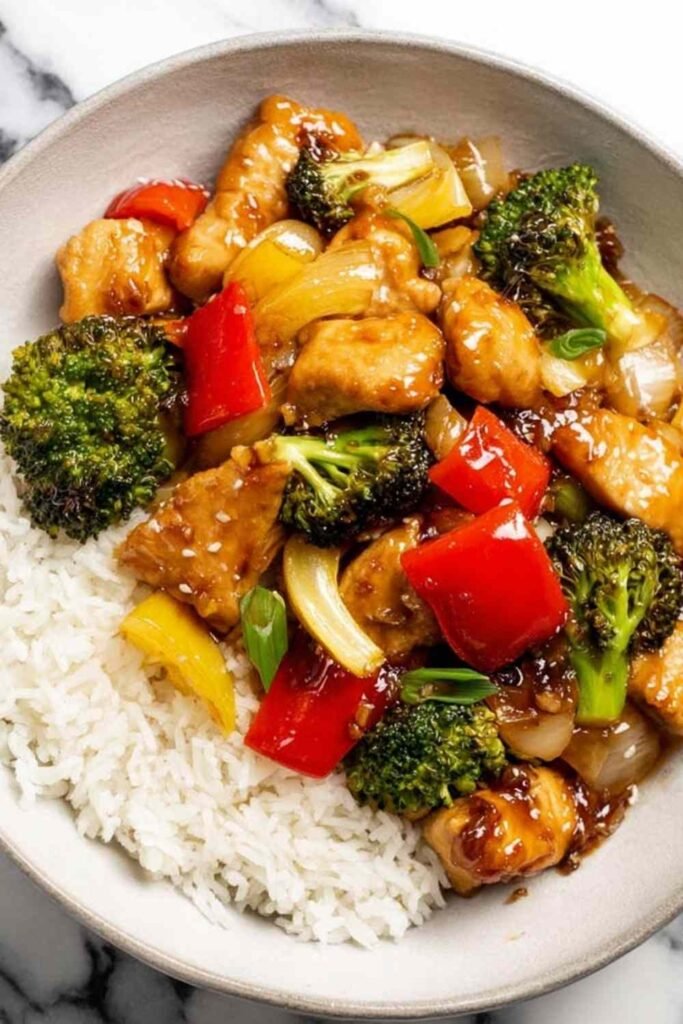 Teriyaki chicken stir fry with broccoli and red bell pepper in a deep skillet coated in homemade sticky teriyaki sauce