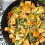 Tofu Vegetable Stir-Fry with Peanut Sauce 3 Crispy tofu vegetable stir-fry with peanut sauce in a large skillet garnished with sesame seeds and green onion
