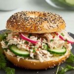 Tuna Everything Bagel 24 Close-up of a fully assembled tuna everything bagel with creamy herb tuna salad, red onion, tomato, cucumber, and Bibb lettuce on a toasted bagel with cream cheese