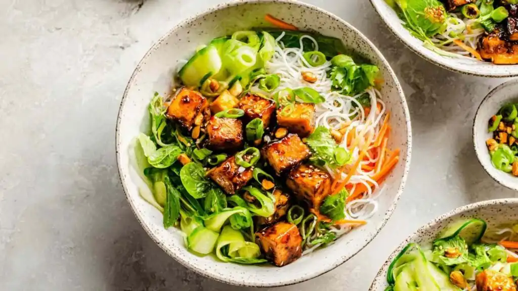 Close-up of a Vietnamese chicken noodle bowl with sliced lemongrass chicken, vermicelli, fresh herbs, and nuoc mam cham dressing