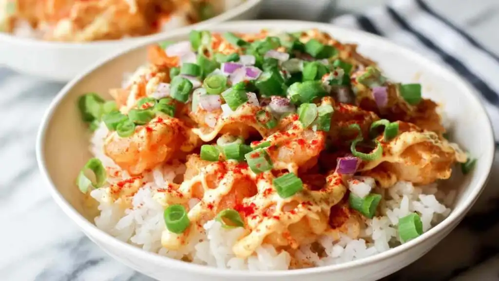 Bang Bang Shrimp Rice Bowls 13 Assembled Bang Bang Shrimp Rice Bowl topped with creamy bang bang sauce, shredded cabbage, diced tomatoes, and green onion