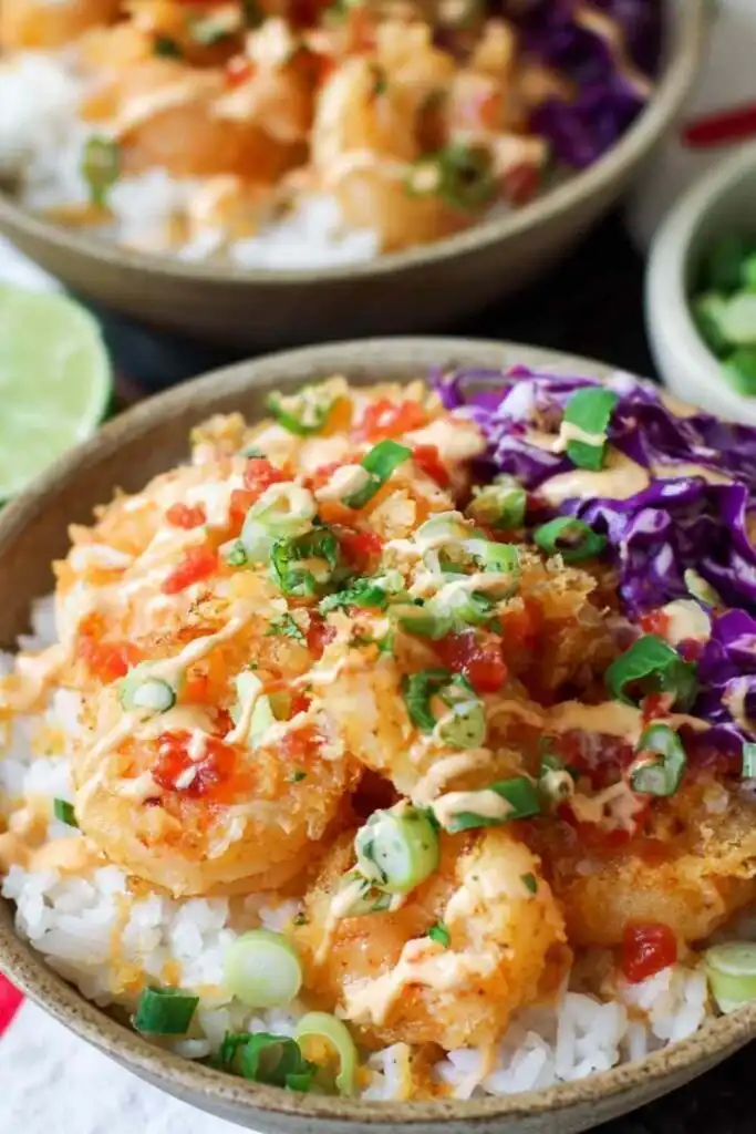 Bang Bang Shrimp Rice Bowls 14 Assembled Bang Bang Shrimp Rice Bowl topped with creamy bang bang sauce, shredded cabbage, diced tomatoes, and green onion