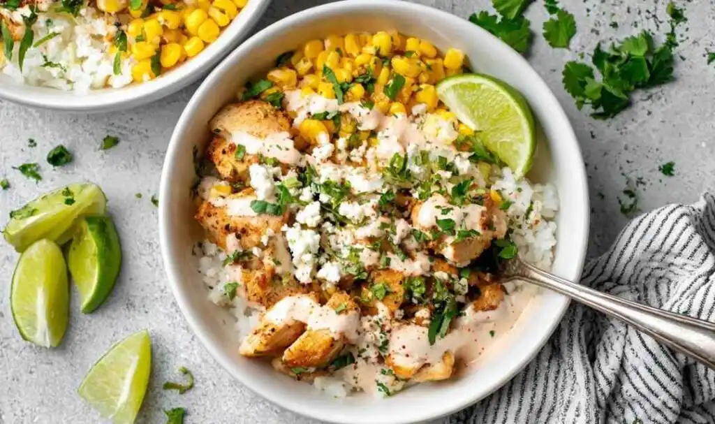 Chicken Corn Rice Bowls 1 High protein chicken corn rice bowl topped with crumbled feta, fresh cilantro, and sour cream dressing served in a white bowl