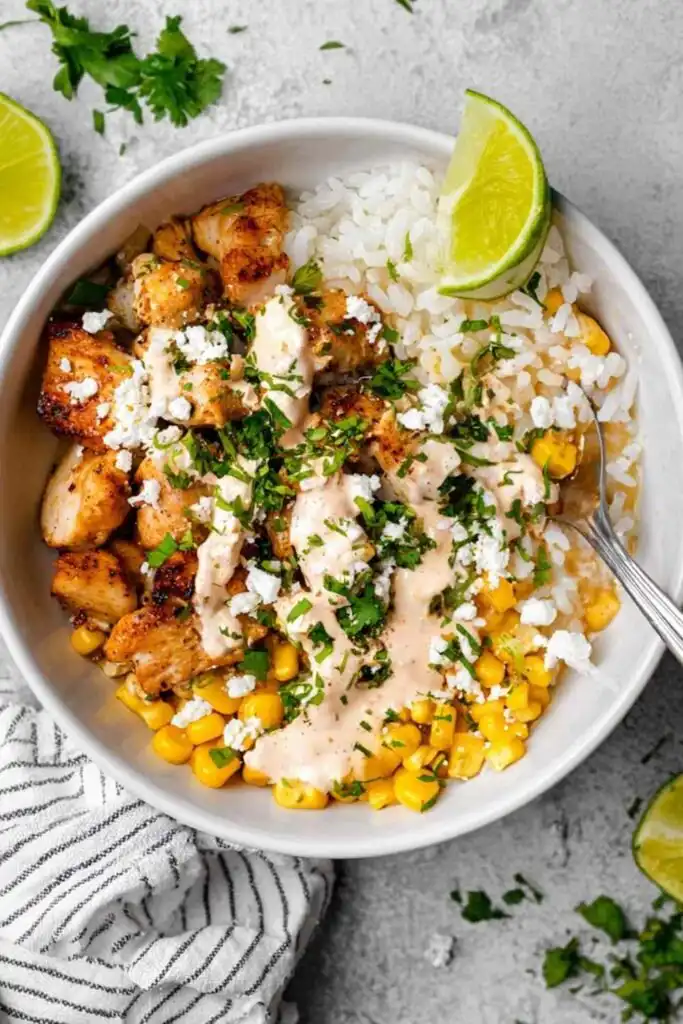 Chicken Corn Rice Bowls 2 High protein chicken corn rice bowl topped with crumbled feta, fresh cilantro, and sour cream dressing served in a white bowl
