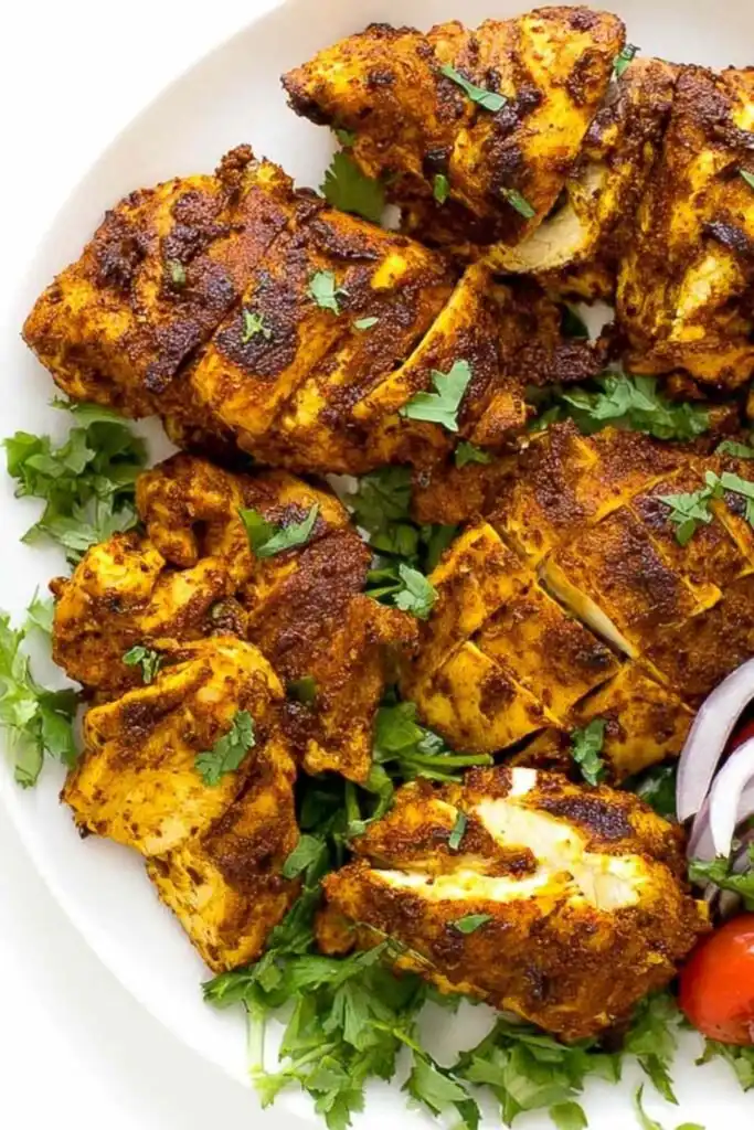 Sliced chicken shawarma on a white plate drizzled with creamy garlic sauce and topped with fresh parsley