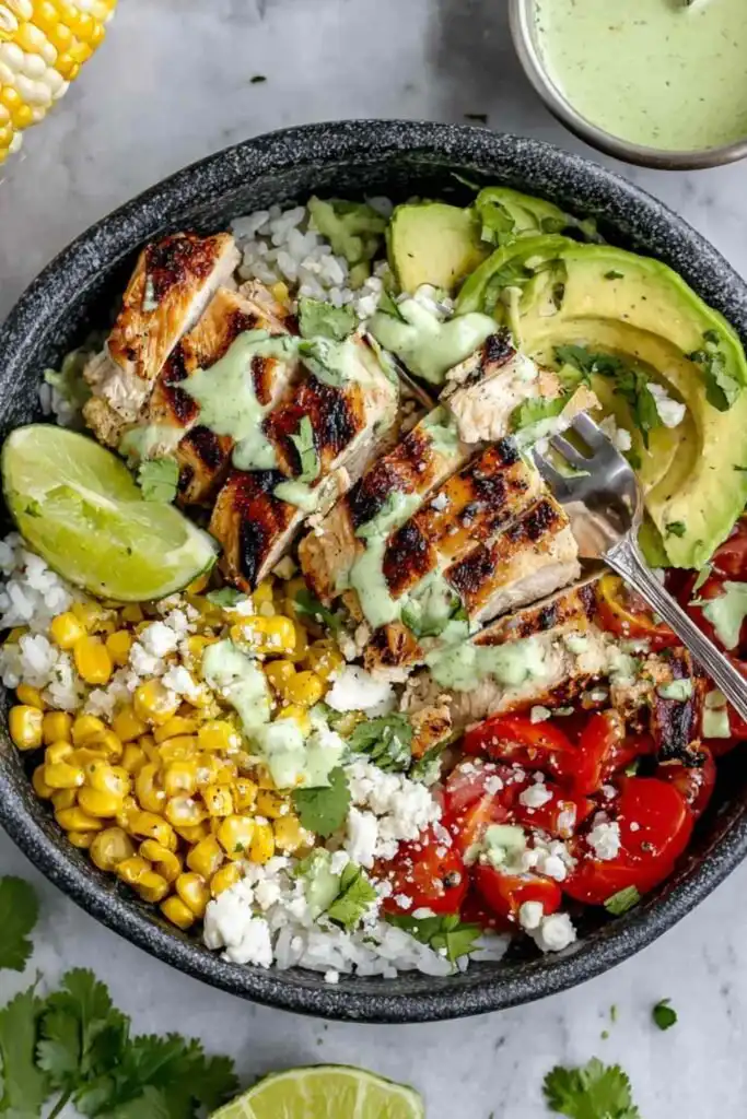 Cilantro Lime Chicken and Rice Bowls with Spicy Green Goddess Dressing 17 Cilantro lime chicken and rice bowl topped with sliced grilled chicken, avocado, cherry tomatoes, grilled corn, cotija cheese, and green goddess dressing