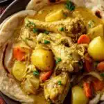 Curry chicken roti served on a plate with shredded coconut curry chicken wrapped in warm flatbread and garnished with fresh cilantro