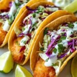 Crispy Baja Fish Tacos 9 Three crispy Baja fish tacos on a wooden board with cabbage slaw, jalapeño lime sauce, and lime wedges